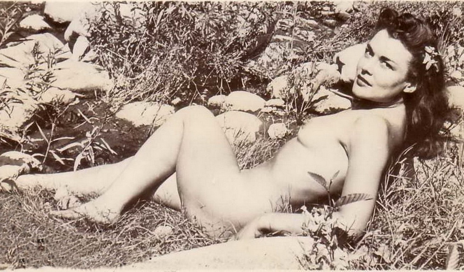 Эротические ретро обои для рабочего стола. обнаженная женщина лежит на траве среди камней