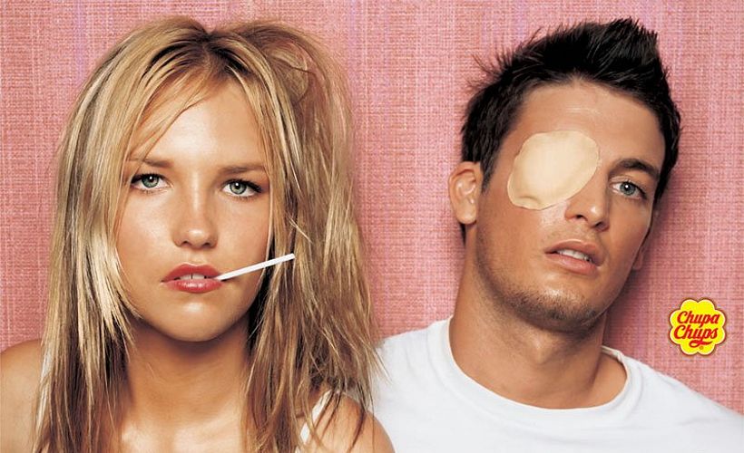 мужчина с поврежденным глазом и девушка не выпускающая изо рта чупа-чупс, сексуальная реклама, эротика в рекламе фото