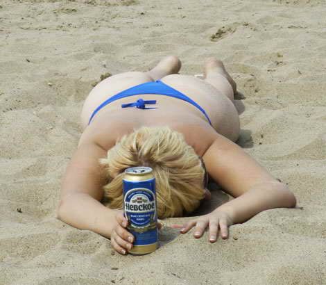 на берегу Невы. пьяная женщина уснула на песке с банкой пива в руках. прикольное красивое женское тело
