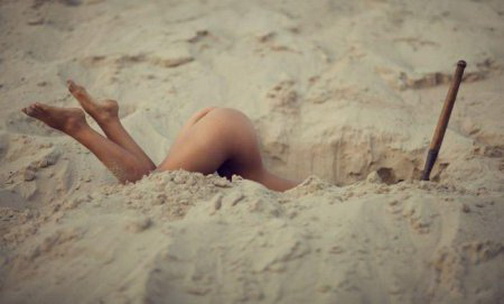 рытье окопов. голая женская попа торчит из вырытой в песке ямы.  красивое женское тело