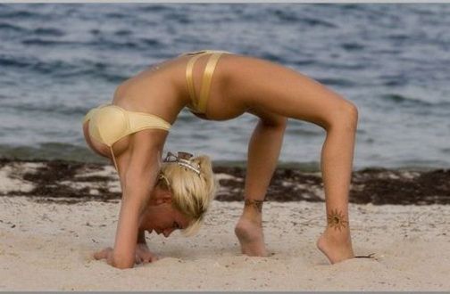 мостик. сисястая девушка делает гимнастическое упражнение мостик на пляже.  красивое женское тело