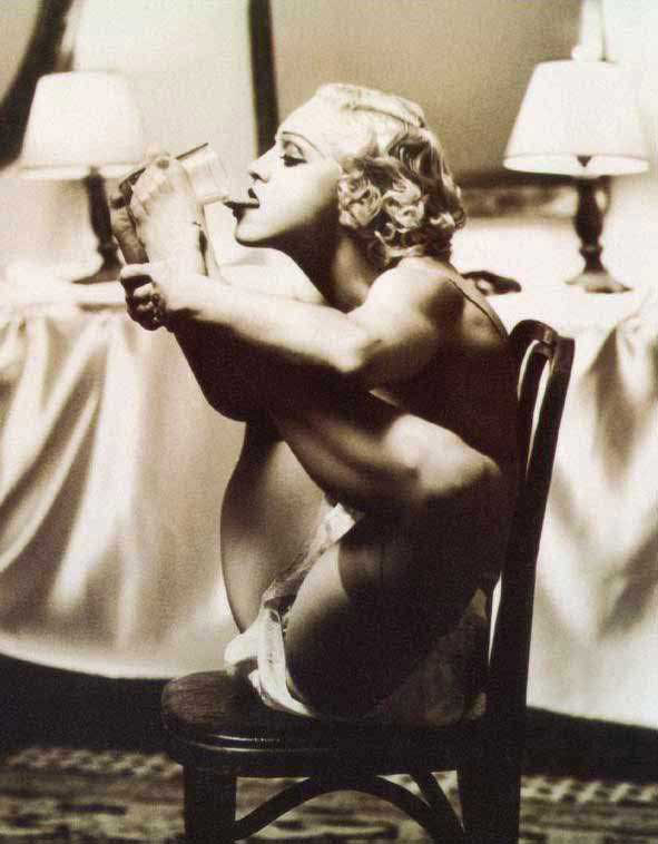 голая Мадонна ногами держит стакан поднося его ко рту