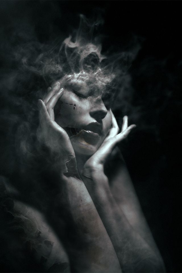 распадающееся в дым лицо девушки-привидения в луче света