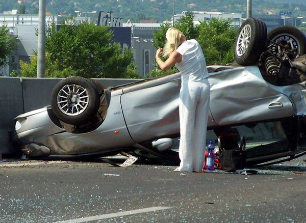 для женщины главное прическа. блондинка прихорашивается стоя у разбитой машины. веселая картинка для взрослых