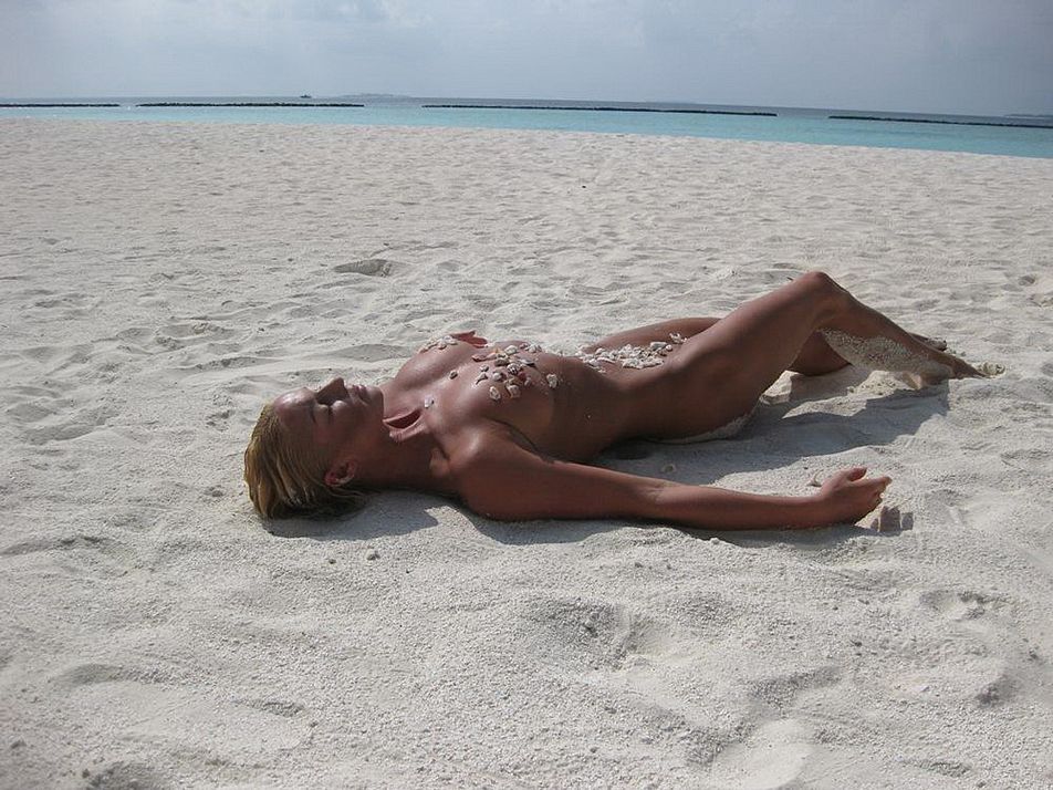 голая Анастасия Волочкова лежит на песке присыпанная камнями