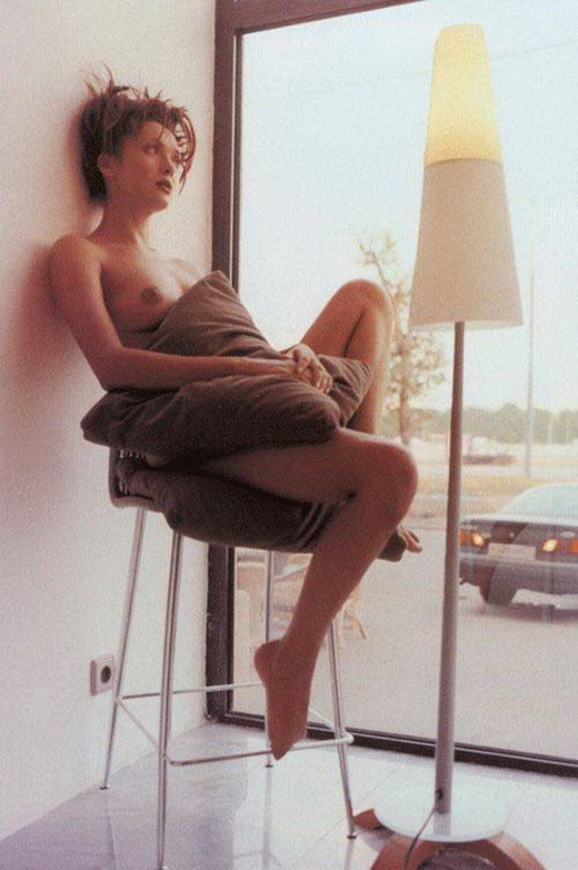 Ольга Дроздова в голом виде сидит на высоком табурете у окна