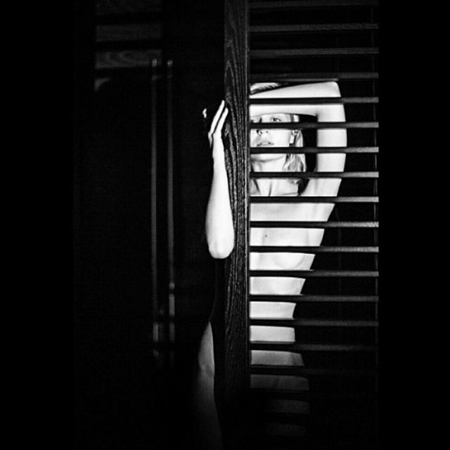 фото черно-белое фото голой Полины Гагариной стоящей в луче света в темной комнате за деревянной перегородкой